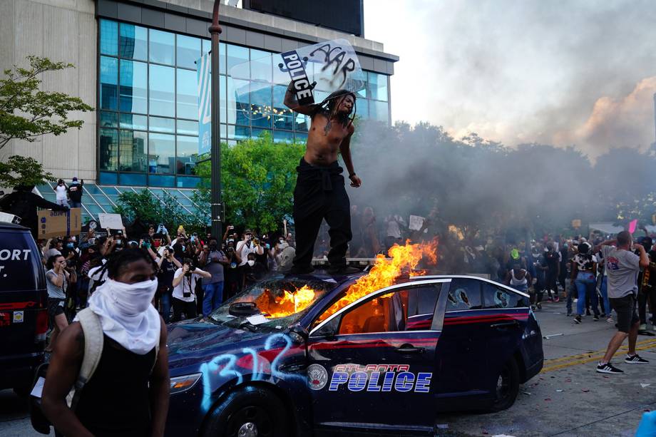 Um manifestante sobe em cima de um carro da polícia em chamas durante um protesto em Atlanta, Geórgia - 29/05/2020 Um manifestante sobe em cima de um carro da polícia em chamas durante um protesto em Atlanta, Geórgia - 29/05/2020