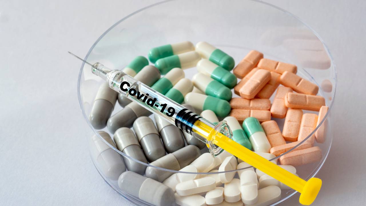 Syringe with covid-19 coronavirus vaccine and medication tablets for symptoms.