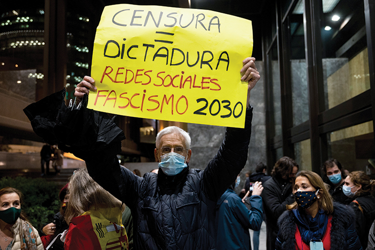 A man wearing a face mask to protect against the spread of PROTESTO - Na Espanha: manifestante compara “censura” às redes sociais com ditadura -