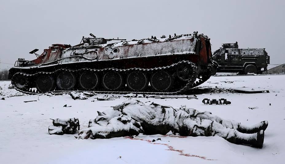 O corpo sem vida de um soldado é visto ao lado de um veículo blindado russo queimado depois que o exército ucraniano o atacou no dia anterior perto da cidade de Kharkiv, na Ucrânia -