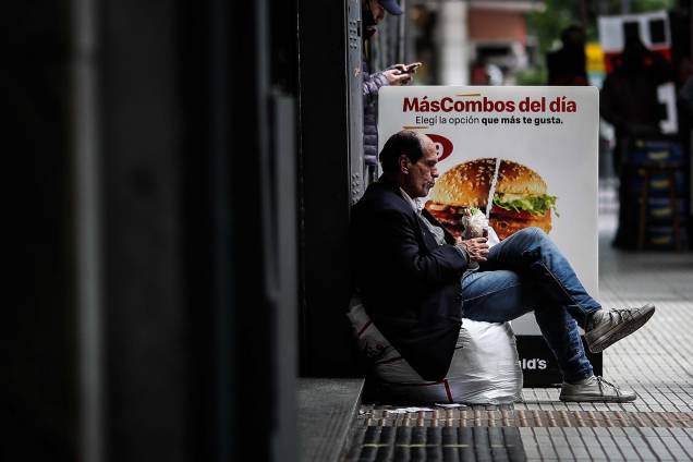 Um homem em situação de rua se alimenta em frente `a um fast food, em Buenos Aires, na Argentina. Um homem em situação de rua se alimenta em frente `a um fast food, em Buenos Aires, na Argentina.