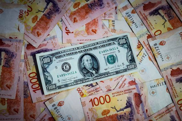 Fotografia comparativa de notas de Peso argentino com uma nota de 100 Dólares. A substituição da moeda local pelo dólar como meio de pagamento ou instrumento de fixação de preços, uma prática que vários países da América Latina têm recorrido. Fotografia comparativa de notas de Peso argentino com uma nota de 100 Dólares. A substituição da moeda local pelo dólar como meio de pagamento ou instrumento de fixação de preços, uma prática que vários países da América Latina têm recorrido.