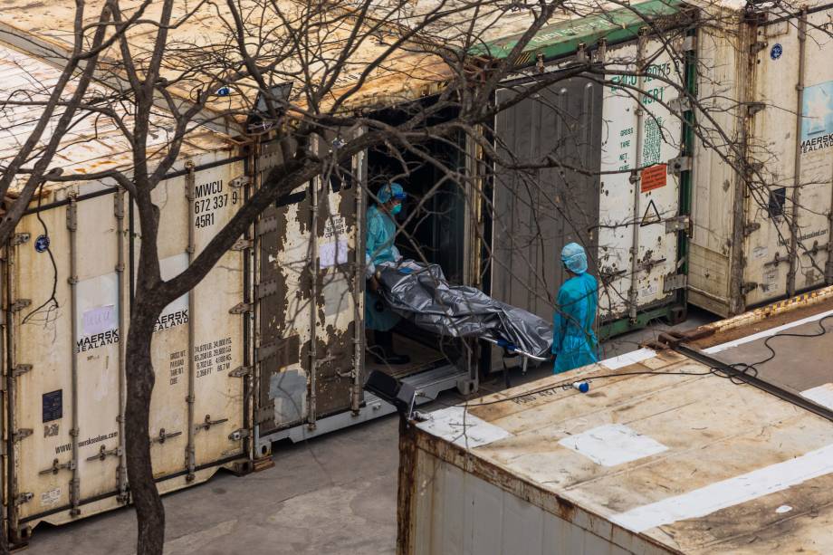 Trabalhadores do serviço de saúde carregam o corpo de uma pessoa para um contêiner refrigerado, no necrotério público de Fu Shan, em Hong Kong, em 16 de março de 2022, em meio ao pior surto de Coronavírus Covid-19.