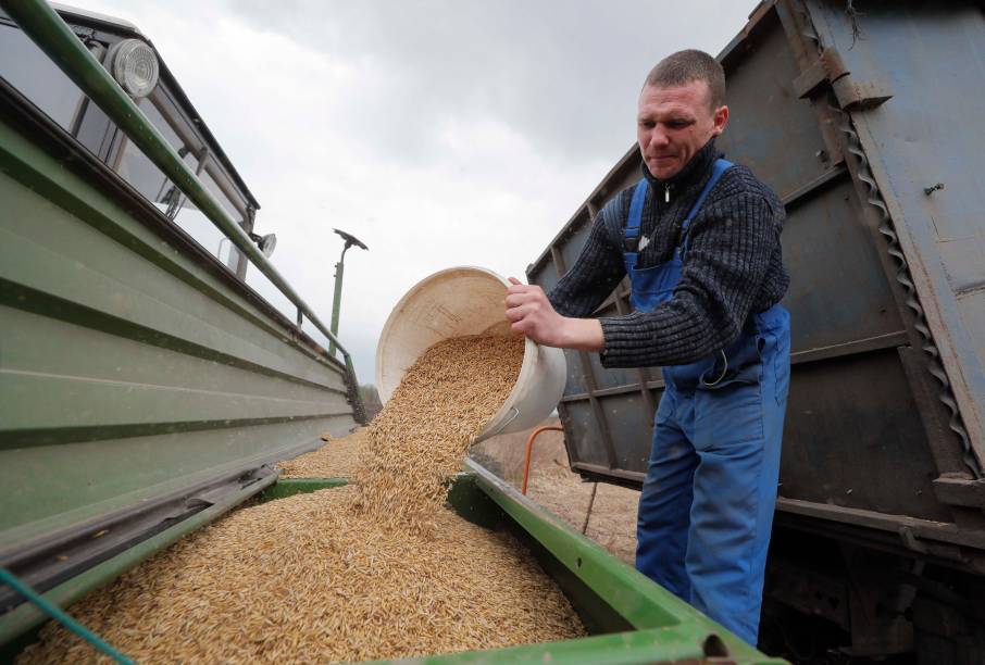 Um agricultor derrama um balde de grãos em um campo nos arredores de Kiev, Ucrânia, 16 de abril de 2022. Agricultores ucranianos começaram a trabalhar em seus campos, em meio à invasão russa do país.