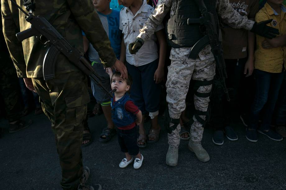 Uma criança palestina olha para um membro das Brigadas al-Qassam, o braço armado do movimento Hamas, em Rafah, no sul da Faixa de Gaza. 2021.