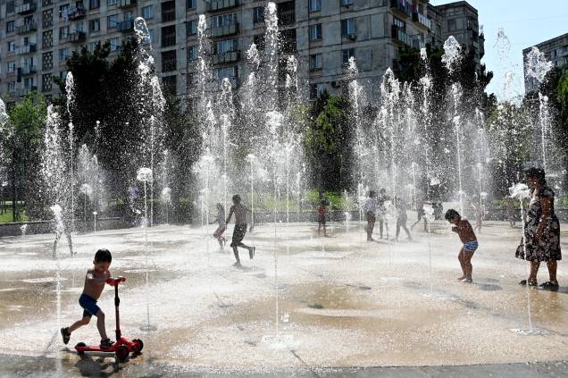 Pessoas se refrescam com a água de uma fonte em Tbilisi em 09/07/2022, quando a temperatura do ar se aproxima de 30 graus Celsius. Pessoas se refrescam com a água de uma fonte em Tbilisi em 09/07/2022, quando a temperatura do ar se aproxima de 30 graus Celsius.