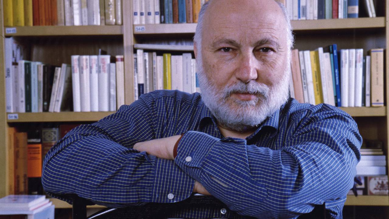 Domenico De Masi no escritório de sua casa em Roma, diante de uma estante de livros