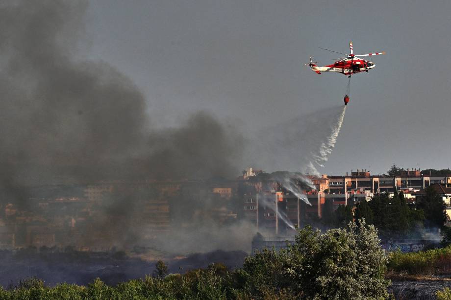 O helicóptero de um bombeiro jogando água para apagar um incêndio que eclodiu no parque Valle Aurelia, em Roma, em 04/07/2022. O helicóptero de um bombeiro jogando água para apagar um incêndio que eclodiu no parque Valle Aurelia, em Roma, em 04/07/2022.