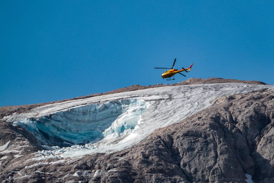 Um helicóptero de resgate sobrevoa sobre a geleira que desabou no dia anterior na montanha de Marmolada, a mais alta das Dolomitas, um dia após uma temperatura recorde ser registrada no cume da geleira. Um helicóptero de resgate sobrevoa sobre a geleira que desabou no dia anterior na montanha de Marmolada, a mais alta das Dolomitas, um dia após uma temperatura recorde ser registrada no cume da geleira.