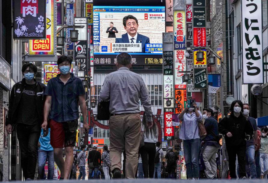 Pessoas caminham por uma rua de Kabukicho, o maior distrito de entretenimento noturno do Japão em Shinjuku em Tóquio, na TV o ex primeiro-ministro japonês Shinzo Abe suspende o estado de emergência no país, após uma queda nos casos de coronavírus. 25/05/2020. Pessoas caminham por uma rua de Kabukicho, o maior distrito de entretenimento noturno do Japão em Shinjuku em Tóquio, na TV o ex primeiro-ministro japonês Shinzo Abe suspende o estado de emergência no país, após uma queda nos casos de coronavírus. 25/05/2020.