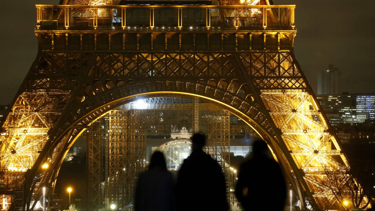PARIS, FRANCE - JANUARY 14: People look at the illuminated Eiffel Tower at night as French Prime Minister, Jean Castex announces measures to combat the coronavirus (COVID-19) outbreak on January 14, 2021 in Paris, France. Jean Castex announced that a 6 p.m. curfew would apply throughout mainland France as of Saturday January 16. Vaccination will be extended from Monday to people suffering certain chronic conditions. Seven hundred vaccination centers will be open in France from January 18, according to the Prime Minister. (Photo by Chesnot/Getty Images)