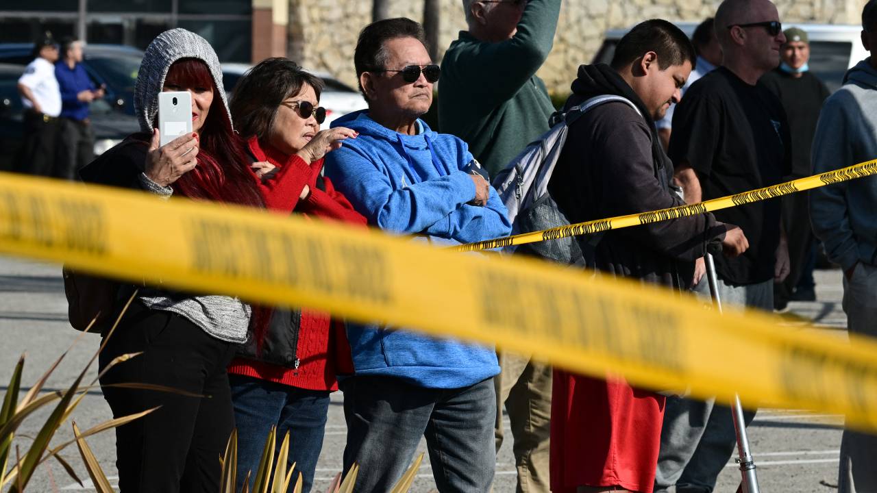 Bystanders watch law enforcement agents breaking into a van with a body in the driver's seat in Torrance, California, on January 22, 2023. - California police hunting the gunman who killed 10 people at a dance club during Lunar New Year celebrations broke into a van after a lengthy standoff Sunday, where images showed a body slumped in the driver's seat. The hunt began 12 hours earlier after a man -- described by police as Asian -- began firing at a club in Monterey Park, a city in Los Angeles County with a large Asian community. (Photo by Robyn BECK / AFP)