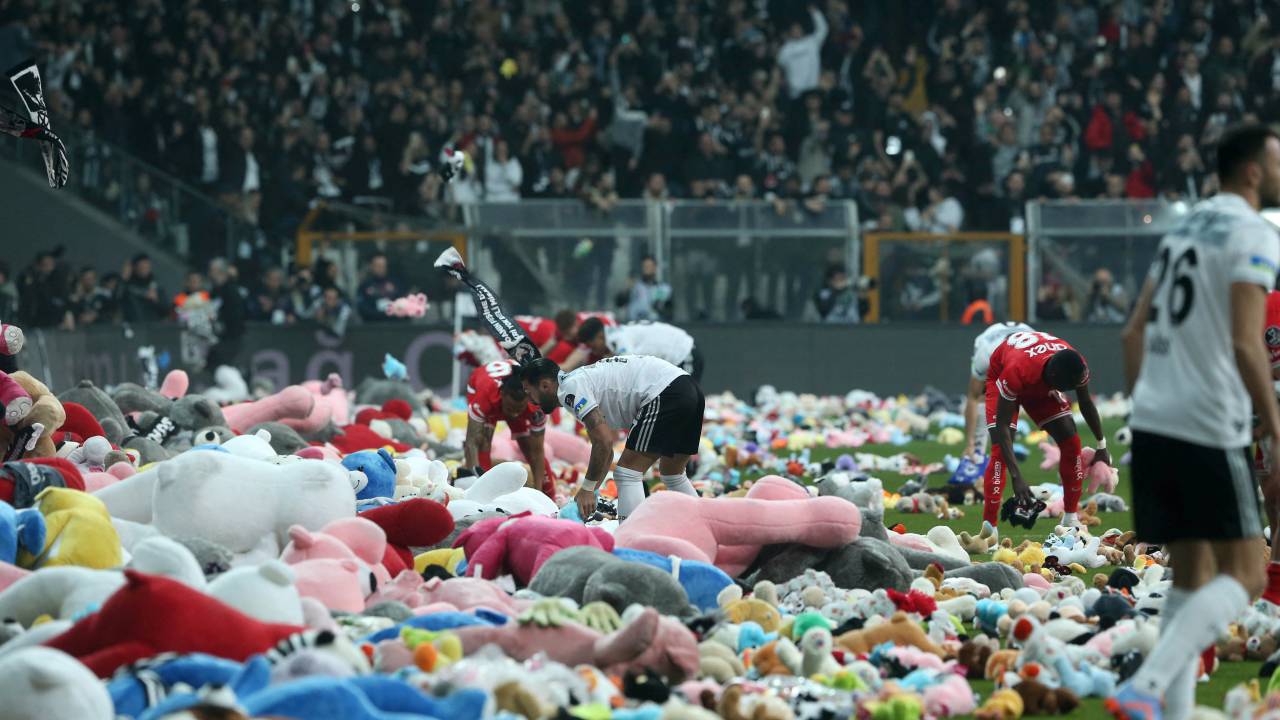 This handout photograph taken and released by Turkish agency DHA (Demiroren News Agency) on February 26, 2023 shows players collecting toys from the pitch as Besiktas fans throw toys onto the pitch during the Turkish Super League soccer match between Besiktas and Antalyaspor at the Vodafone stadium in Istanbul. - Besiktas supporters threw a massive number of soft toys to be donated to children affected by the powerful earthquake on Feb. 6 on southeast Turkey. (Photo by Handout / DHA (Demiroren News Agency) / AFP) / - Turkey OUT / RESTRICTED TO EDITORIAL USE - MANDATORY CREDIT "AFP PHOTO / DHA (DEMIROREN NEWS AGENCY) " - NO MARKETING NO ADVERTISING CAMPAIGNS - DISTRIBUTED AS A SERVICE TO CLIENTS