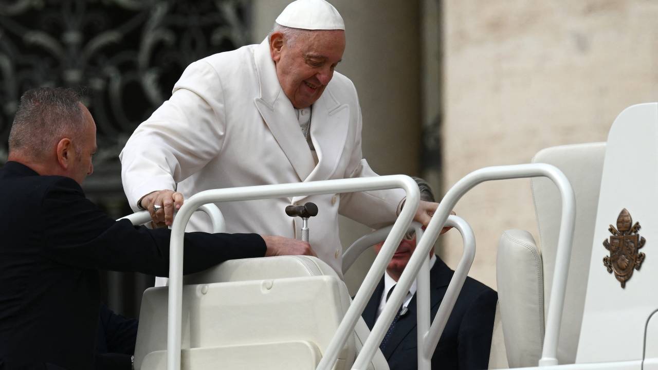 Pope Francis is helped get up the popemobile car as he leaves on March 29, 2023 at the end of the weekly general audience at St. Peter's square in The Vatican. - Pope Francis has been at the Gemelli Hospital in Rome since the afternoon of March 29, 2023 for some previously scheduled check-ups, the Holy See press director said. (Photo by Vincenzo PINTO / AFP)
