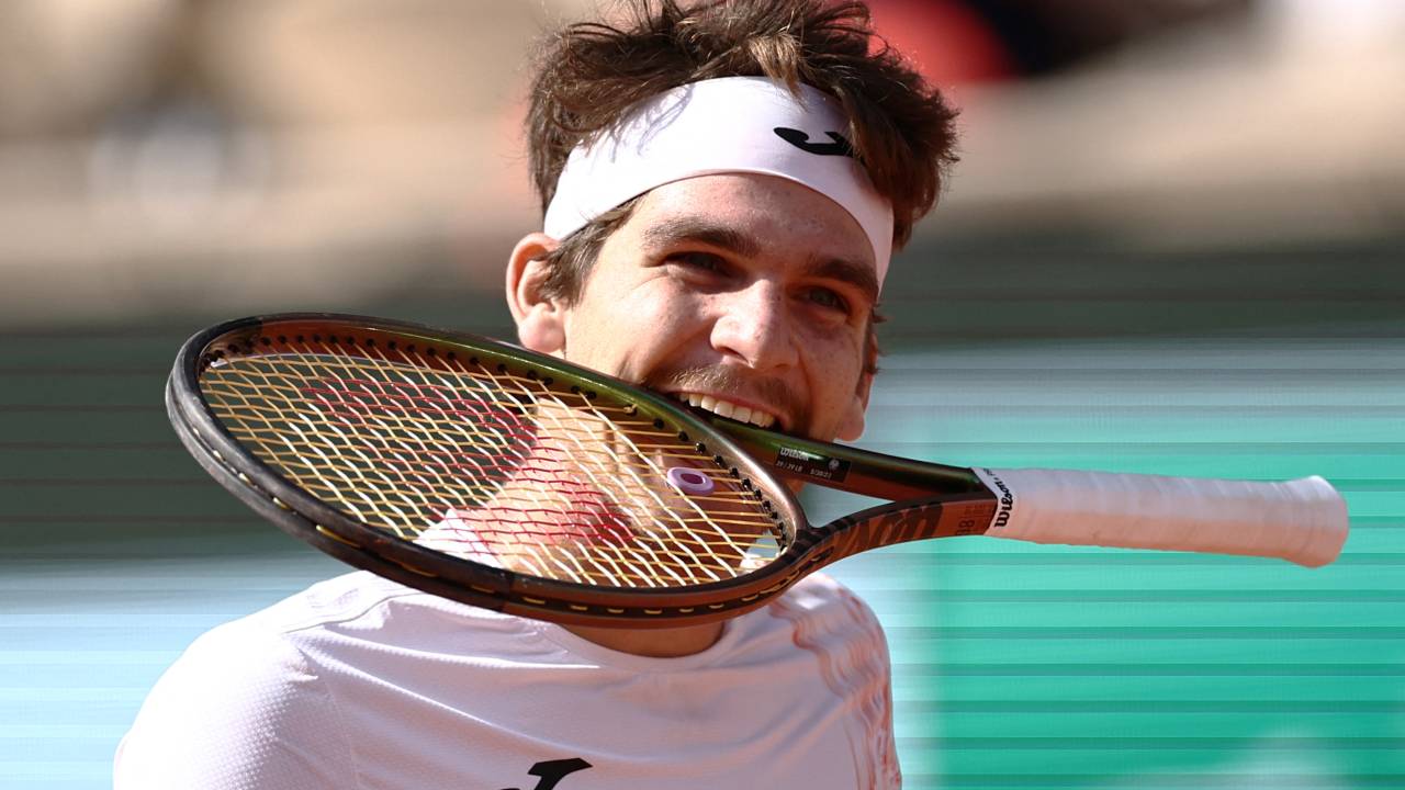 Brazil's Thiago Seyboth Wild bites his racket during his match against Russia's Daniil Medvedev during their men's singles match on day three of the Roland-Garros Open tennis tournament at the Court Philippe-Chatrier in Paris on May 30, 2023. (Photo by Anne-Christine POUJOULAT / AFP)