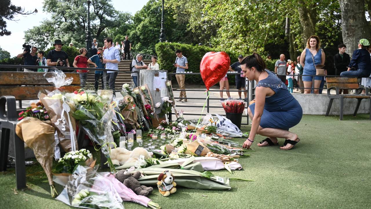 A woman lays flowers for the victims of a stabbing attack that occured the day before in the 'Jardins de l'Europe' parc in Annecy, French Alps, on June 9, 2023. A man armed with a knife stabbed four preschool children and injured two adults by a lake in the French Alps on June 8 in an attack that sent shock waves through the country. The suspect is a Syrian in his early 30s who was granted refugee status in Sweden in April, a police source told AFP. He was arrested at the scene. (Photo by OLIVIER CHASSIGNOLE / AFP)
