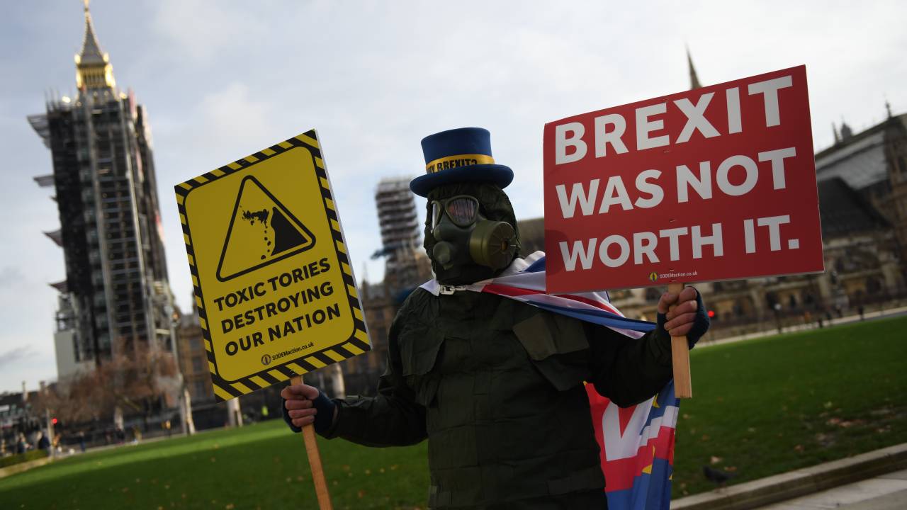 LONDON, ENGLAND - DECEMBER 30: Anti Brexit campaigner, Steve Bray holds placards while wearing a gas mask outside parliament on December 30, 2020 in London, England. The United Kingdom and the European Union agreed a Trade and Cooperation Agreement, an Agreement on Nuclear Cooperation and an Agreement on Security Procedures for Exchanging and Protecting Classified Information on Christmas Eve 2020. These Agreements change the basis of the UK's relationship with the EU from EU law to free trade and friendly cooperation. In a referendum of 23 June 2016 the British people voted to take back control of their laws, borders, money, trade and fisheries, commonly referred to as Brexit. (Photo by Chris J Ratcliffe/Getty Images)