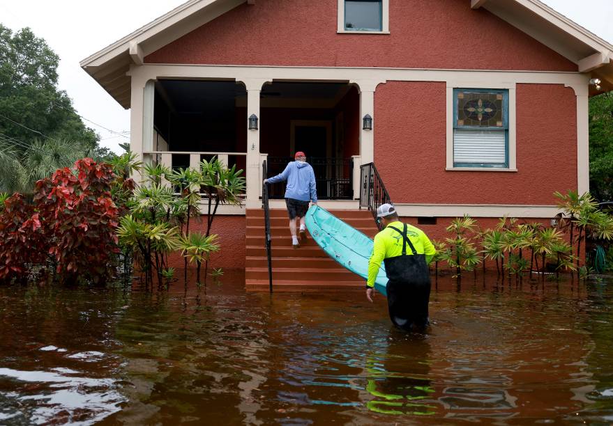 Vizinhos se ajudam a carregar um caiaque até a varanda pelas ruas inundadas de Tarpon Springs, Flórida. 31/08/2023 -