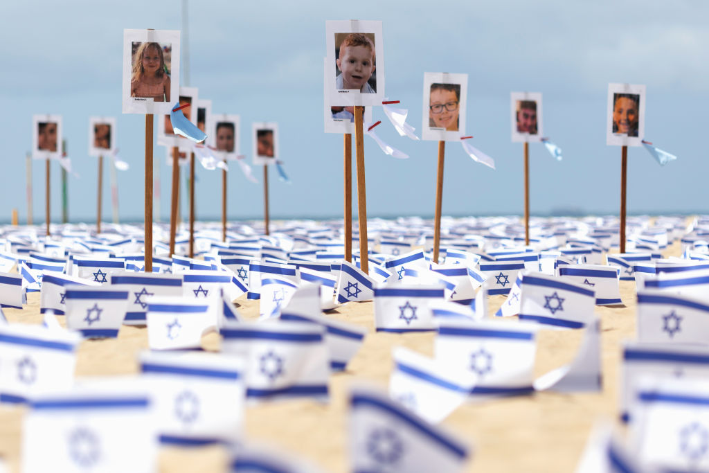 07 November 2023, Brazil, Rio De Janeiro: Pictures of young children who are believed to have died in the current Middle East conflict stand next to Israeli flags on Copacabana beach one month after the major attack by Hamas on Israel. The memorial event was organized by the Brazilian NGO Rio de Paz. Photo: Joao Gabriel Alves/dpa (Photo by Joao Gabriel Alves/picture alliance via Getty Images)