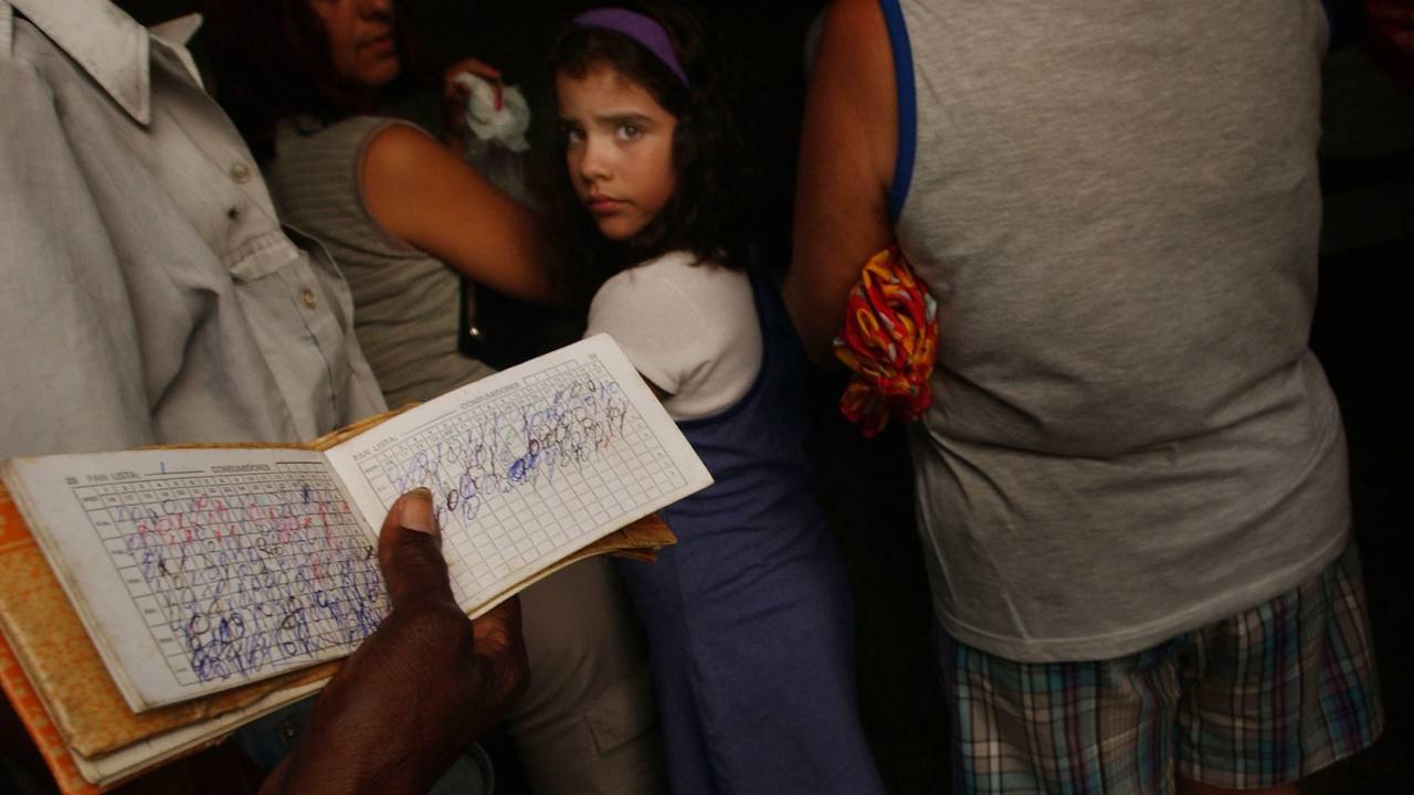 PINAR DEL RIO, CUBA - OCTOBER 5: A person holds out a food rations card October 5, 2002 in Pinar Del Rio, Cuba. New U.S. food sales to communist Cuba reached nearly $90 million last week at an agribusiness fair aimed at fostering the island's appetite for U.S. farm products and chipping away at the 40-year trade embargo. Cuba, an island nation of over 11 million, is still considered by the U.S. to be a Cold War adversary. (Photo by Spencer Platt/Getty Images)