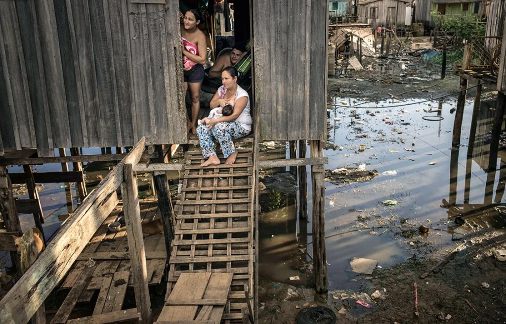Criança caminha próximo ao esgoto, no Complexo da Maré, no Rio de Janeiro