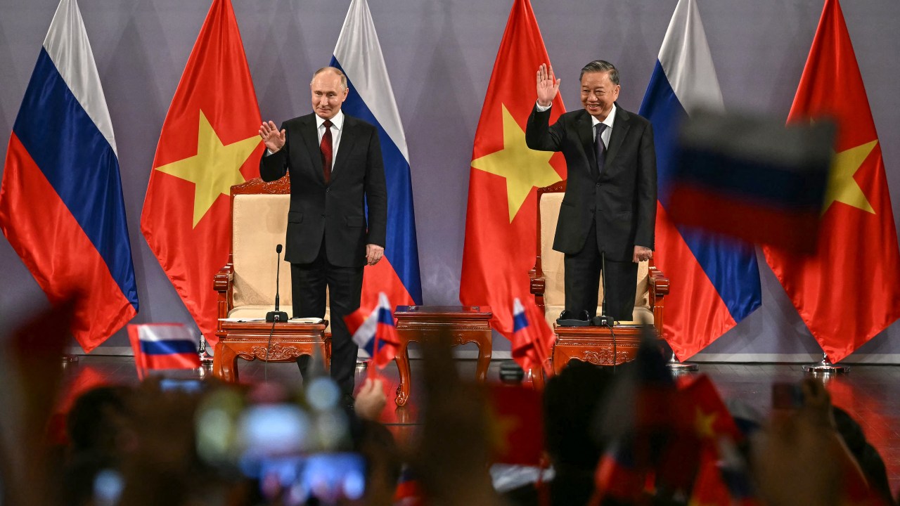 Russia's President Vladimir Putin (L) and Vietnam's President To Lam (R) wave during an event attended by the Vietnam Friendship Association and generations of Vietnamese alumni that studied in Russia at the Hanoi Opera House in Hanoi on June 20, 2024. (Photo by Manan VATSYAYANA / POOL / AFP)