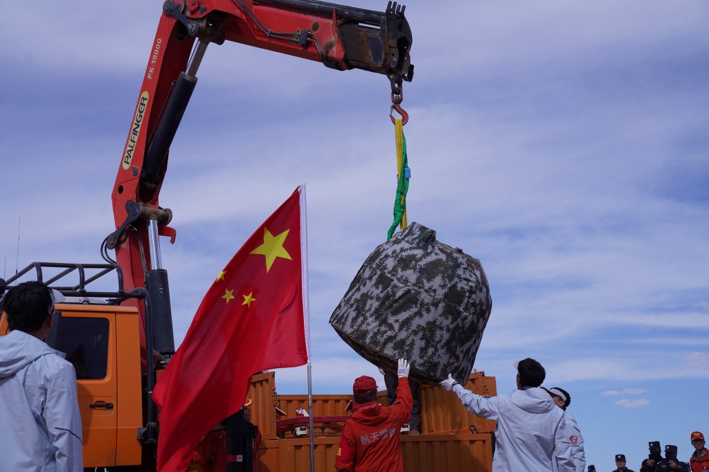 Officials load the landing module of the Changíe-6 moon probe onto a truck after it landed in Inner Mongolia, in northern China on June 25, 2024. A Chinese probe carrying samples from the far side of the Moon returned to Earth on June 25, capping a technically complex 53-day mission heralded as a world first. (Photo by AFP) / China OUT