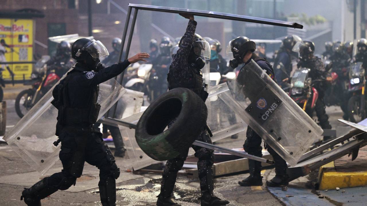 Police officers remove debris during a protest against Venezuelan President Nicolas Maduro's government in Caracas on July 29, 2024, a day after the Venezuelan presidential election. Protests erupted in parts of Caracas Monday against the re-election victory claimed by Venezuelan President Nicolas Maduro but disputed by the opposition and questioned internationally, AFP journalists observed. (Photo by Yuri CORTEZ / AFP)