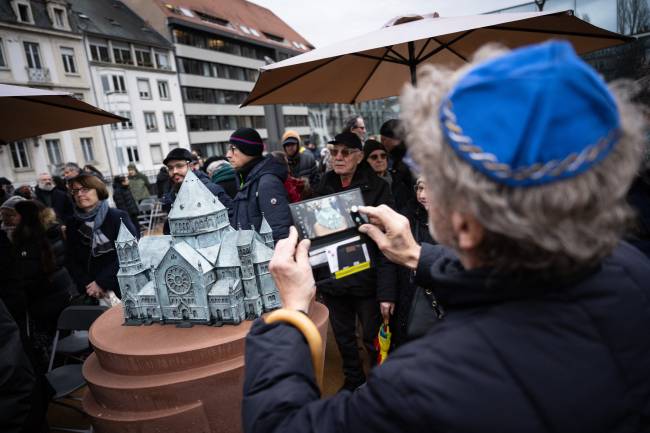 A man takes a picture of a model of the local synagogue destroyed by the Nazis during the inauguration of the Memorial Gardens in Strasbourg, eastern France on January 27, 2025, as nations marked the 80th anniversary of the liberation of the Auschwitz extermination camp in Poland. (Photo by SEBASTIEN BOZON / AFP)