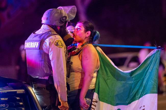 US-POLITICS-IMMIGRATION A protester faces off with a Sheriff deputy amid clashes with law enforcement in the streets surrounding the federal building during a protest following federal immigration operations in Los Angeles, California, on June 8, 2025. Demonstrators torched cars and scuffled with security forces in Los Angeles on June 8, as police kept protestors away from the National Guard troops President Donald Trump sent to the streets of the second biggest US city. (Photo by RINGO CHIU / AFP)