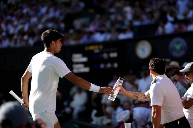LONDON, ENGLAND - JUNE 30: Carlos Alcaraz of Spain passes his waterbottle to a member of security following an incident in the stands during the Gentlemen's Singles first round match against Fabio Fognini of Italy on day one of The Championships Wimbledon 2025 at All England Lawn Tennis and Croquet Club on June 30, 2025 in London, England. (Photo by Julian Finney/Getty Images)